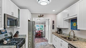 A modern kitchen with white cabinetry, stainless steel appliances, and a granite countertop.