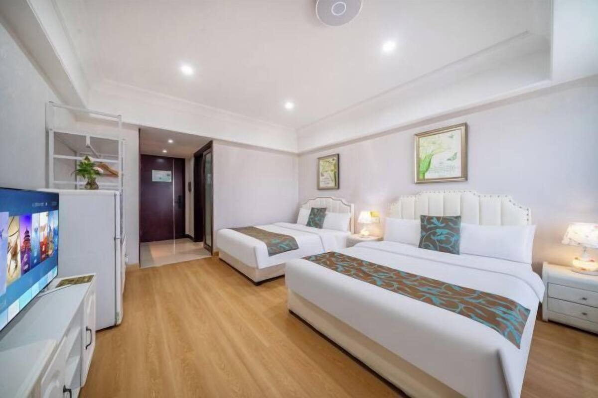 Ein Hotelzimmer mit zwei Betten, einem Fernseher, einem Schreibtisch und einem Kleiderschrank.