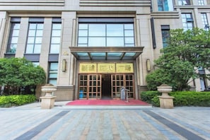 Un edificio con una entrada amplia, una alfombra roja y un letrero con caracteres chinos.