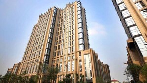 A high-rise building with a grid-like facade, multiple windows, and a well-maintained surrounding area with greenery and a clear sky. - Hangzhou Guteng Condo ApartHotel (Hangzhou)