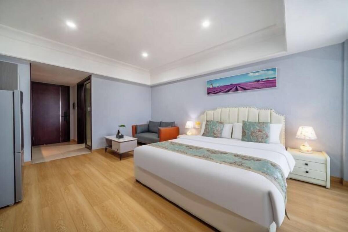 Ein Schlafzimmer mit einem großen Bett, Nachttischen, einem Schranken und einem Bild an der Wand.