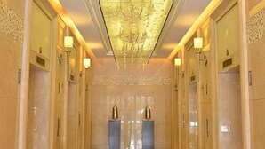 A hallway with a chandelier, wall sconces, and a patterned wall. - Hangzhou Guteng Condo ApartHotel (Hangzhou)