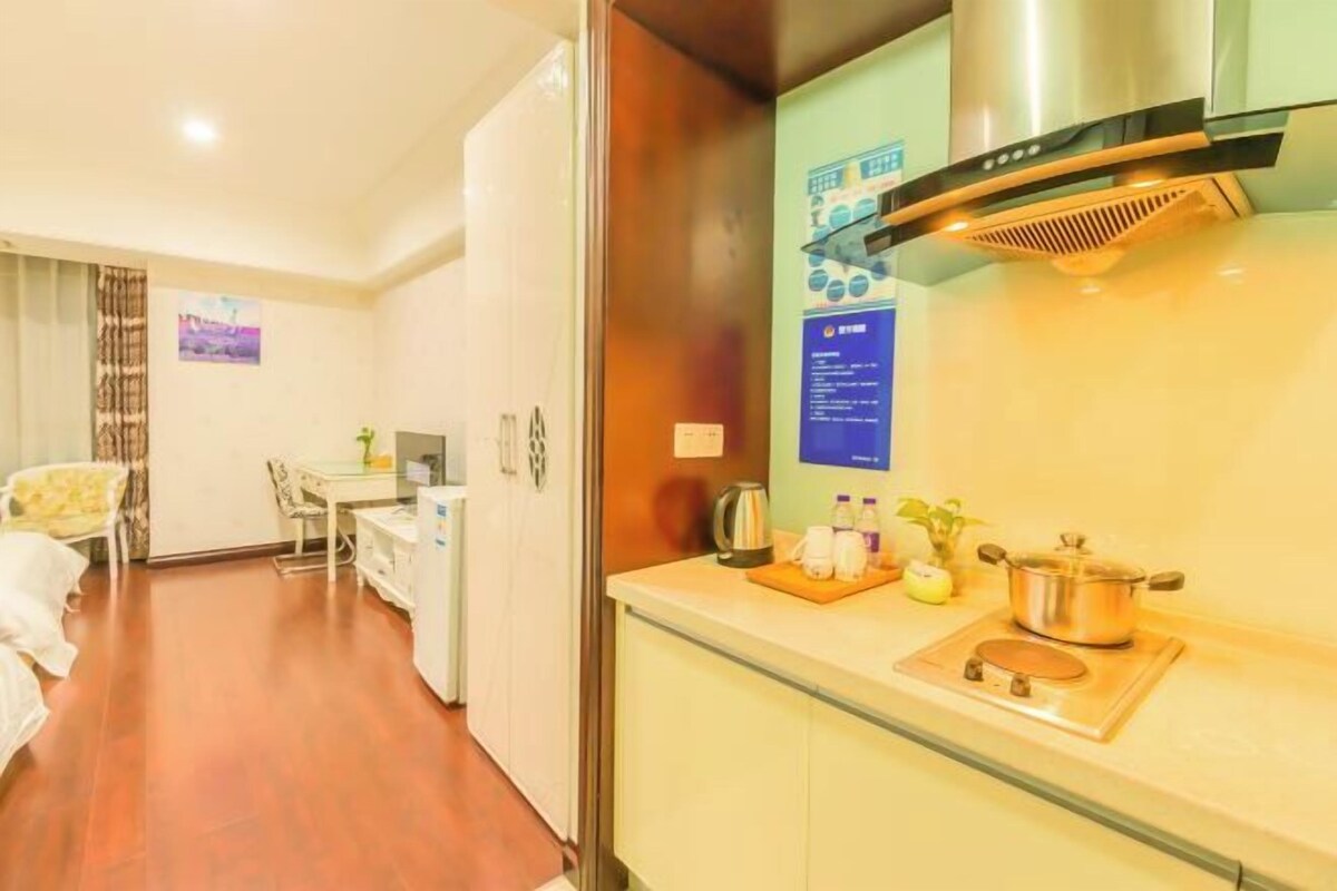 Una habitación de hotel con kitchenette, cama, escritorio y silla.