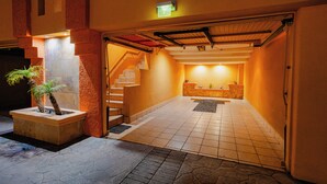 Een hotel lobby met een receptiebalie, een trap en een kleine plantenbak met een palmboom.