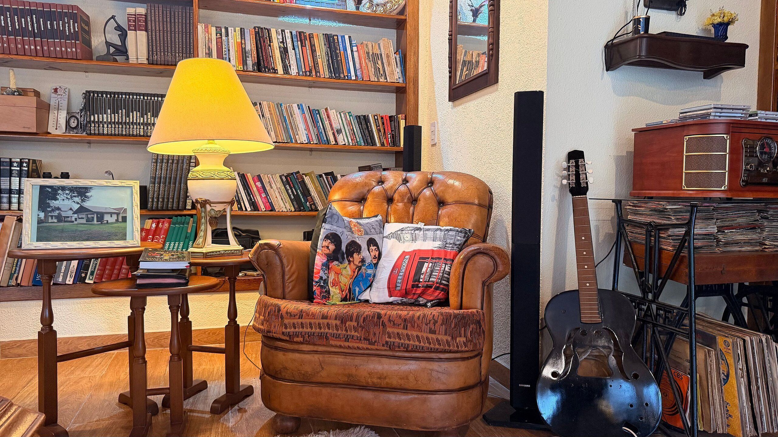 A cozy reading nook with a leather armchair, a table with a lamp, and a bookshelf filled with books.