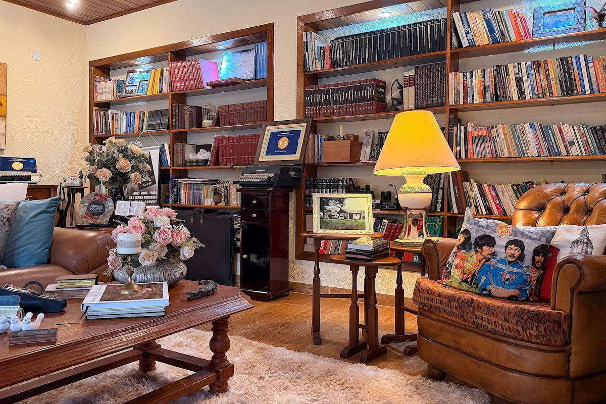 A cozy living room with a leather sofa, a wooden coffee table, and a bookshelf filled with books.