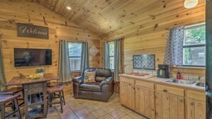 A wooden cabin interior with a living area, a kitchen, and a dining space. - Cozy cabin 1 bedroom, WiFi, AC above Sylamore Creek in welcoming Mountain View (Mountain View)