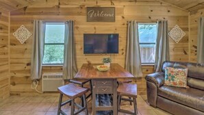 A wooden cabin interior with a dining table, two chairs, a sofa, and a TV. - Cozy cabin 1 bedroom, WiFi, AC above Sylamore Creek in welcoming Mountain View (Mountain View)