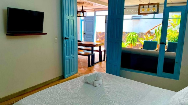 Een hotelkamer met een bed, een televisie en uitzicht op een buitenruimte met beplanting.