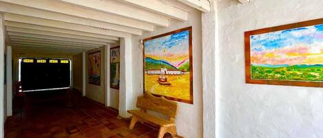 A hallway with a bench, two paintings on the walls, and a tiled floor.
