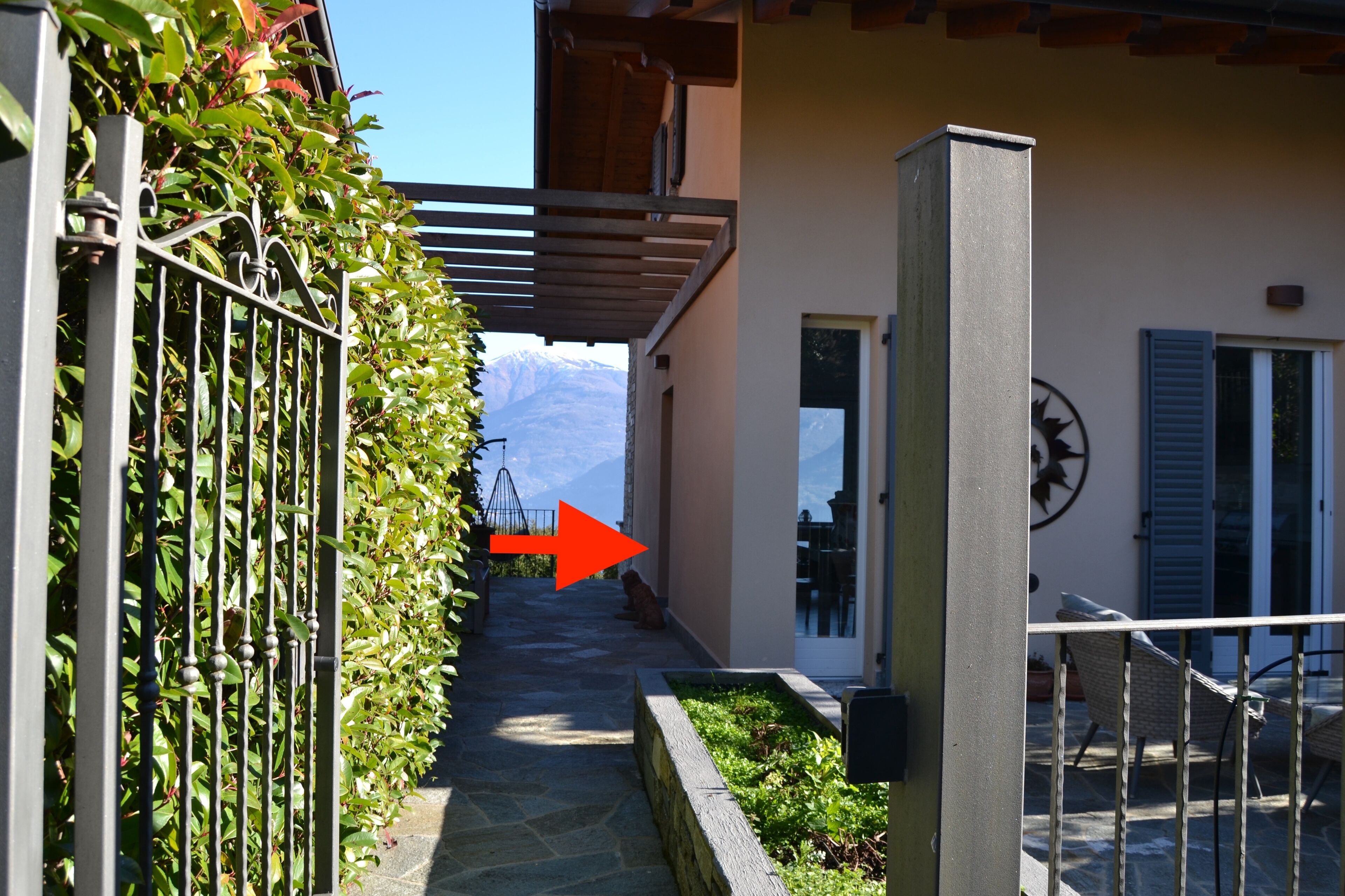 Un étroit sentier menant à un bâtiment doté d’un balcon, d’une porte et offrant une vue sur la montagne.