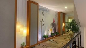 A hallway with a wooden floor, a staircase, and a wall with calligraphy. - Laisili Hotel (Shanghai)