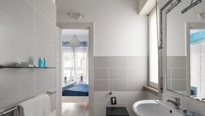 A modern bathroom with a white sink, a mirror, and a towel rack.