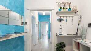 A hallway with a blue wall, a white door, and a shelf with plants and decorative items.