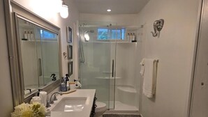 Een moderne badkamer met een dubbele wastafel, een douchecabine met glazen wanden en een grote spiegel.