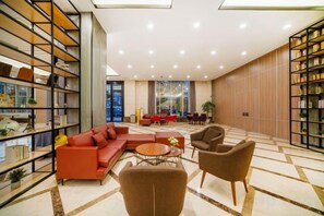 Un rebedor d'hotel modern amb un sofà modular, butaques, una taula de centre i una prestatgeria.