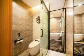 Un bany modern amb un plat de dutxa de vidre, un vàter i un lavabo.