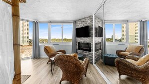 Ein modernes Wohnzimmer mit Rattanmöbeln, einem Kamin und großen Fenstern mit Blick auf die Stadt.