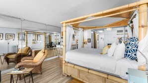 Ein Zimmer mit einem Himmelbett, Korbmöbeln und einem Schreibtisch mit Stuhl.