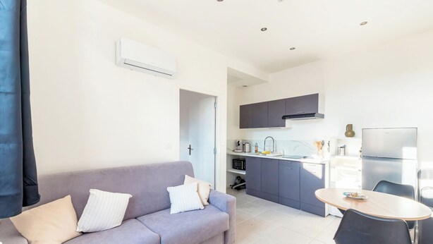 A modern living room with a sofa, a dining table, and a kitchen area with cabinets and appliances. - Charming T2 in the heart of Villeurbanne (Villeurbanne)