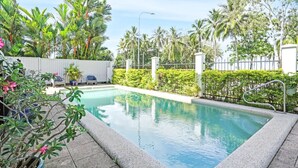A rectangular pool with a white border, surrounded by lush greenery and a white fence. - Ocean Spray- Beachfront Retreat with Ocean Views, Jacuzzi & Pool (Yorkeys Knob)