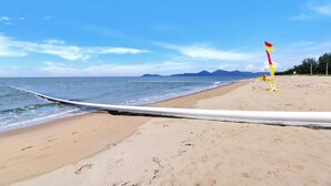 A beach with a white rope barrier, a flag, and footprints in the sand. - Ocean Spray- Beachfront Retreat with Ocean Views, Jacuzzi & Pool (Yorkeys Knob)