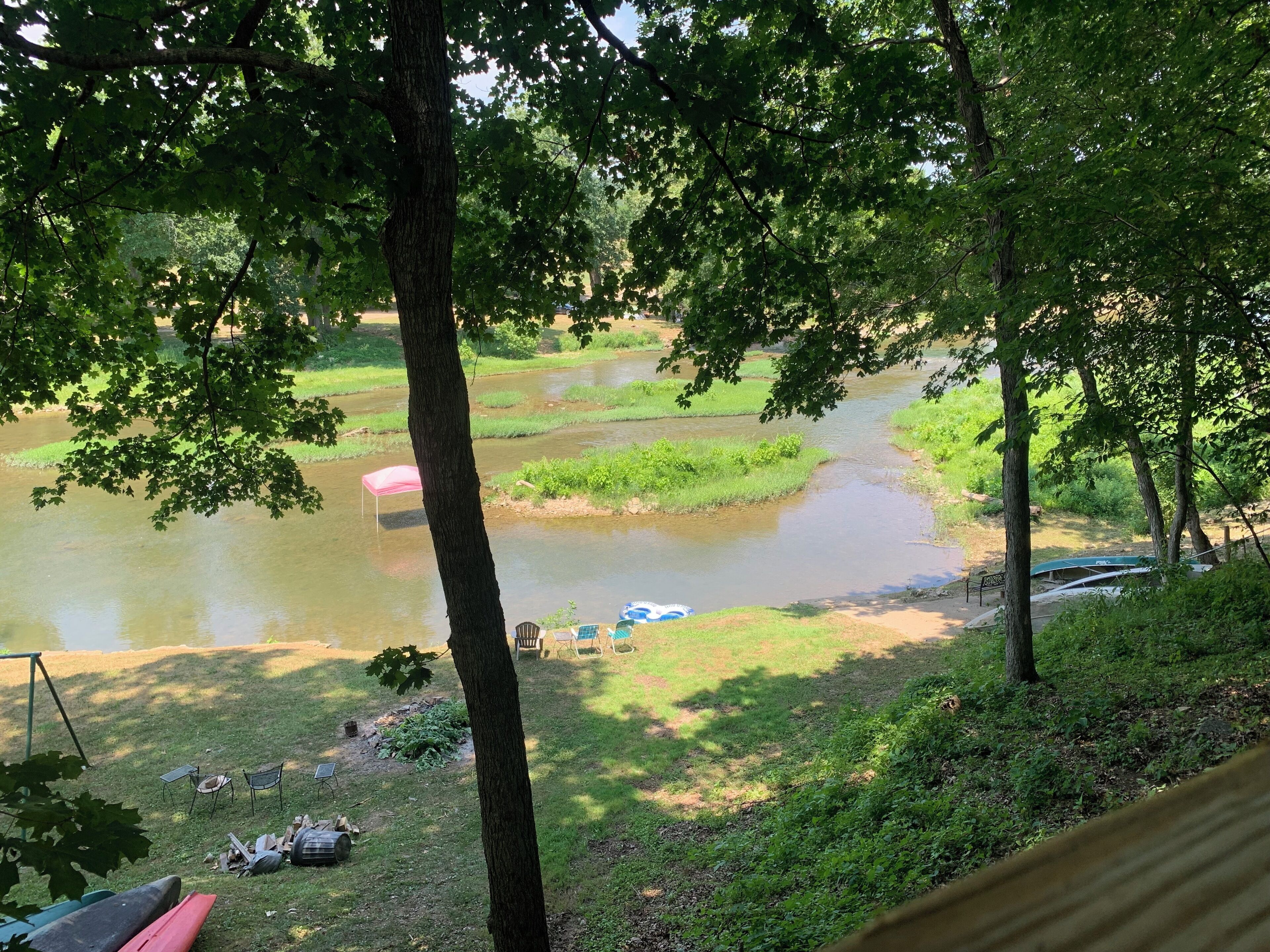 A riverside view with a grassy area, trees, and a small dock.