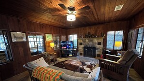 A cozy living room with a fireplace, wooden walls, a television, and a comfortable seating area.