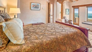 A bedroom with a large bed, wooden ceiling beams, a framed picture on the wall, and a window with a view. - Spacious 4 bedroom with unmatched view! (Angel Fire)