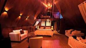 Una habitación amplia y luminosa, con una cama grande, dos sofás, una silla y una mesita.