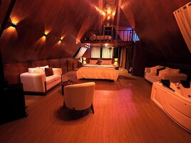 Una habitación amplia y luminosa, con una cama grande, dos sofás, una silla y una mesita.