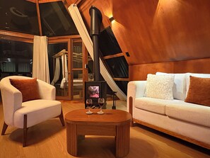 Ein gemütliches Zimmer mit Kamin, einer Couch, einem Sessel und einem Tisch mit Gläsern.