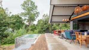 Eine moderne Außenpatio mit Pool, Holzterrasse und Lounge-Bereich mit Sofas und Sesseln.