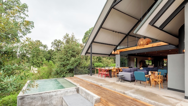 Eine moderne Außenpatio mit Pool, Holzdeck und Sitzbereich mit Tischen und Stühlen.