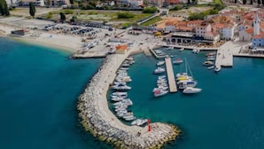 An aerial view of a coastal town with a marina, boats, and buildings. - Modern apartment in a perfect location. Sea and old town within walking distance (Fazana)