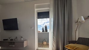 A modern living room with a flat-screen TV, a wooden coffee table, a sofa with a mustard-colored cushion, and a view of the sky and trees through a window. - Modern apartment in a perfect location. Sea and old town within walking distance (Fazana)