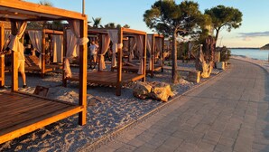 A beachside resort with wooden cabanas, a pebble beach, and a paved walkway. - Modern apartment in a perfect location. Sea and old town within walking distance (Fazana)