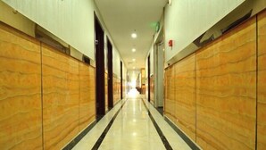 Un couloir d’hôtel avec un sol en marbre et des murs recouverts de panneaux en bois.