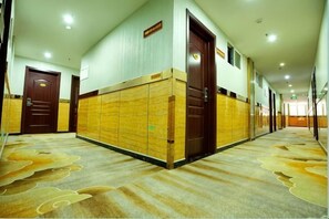 Ein Hotelgang mit Schließfächern, Türen und einem gemusterten Teppich.