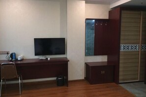Ein Zimmer mit einem Holztisch, einem Fernseher, einem Stuhl und einem Kleiderschrank.