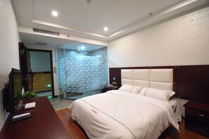 A hotel room with a large bed, a wooden desk, a shower area, and a television.