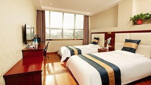 Une chambre d’hôtel avec deux lits, un bureau, une télévision et une grande fenêtre.