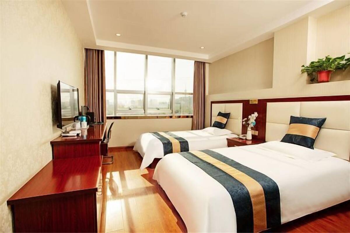 Une chambre d’hôtel avec deux lits, un bureau, une télévision et une grande fenêtre.