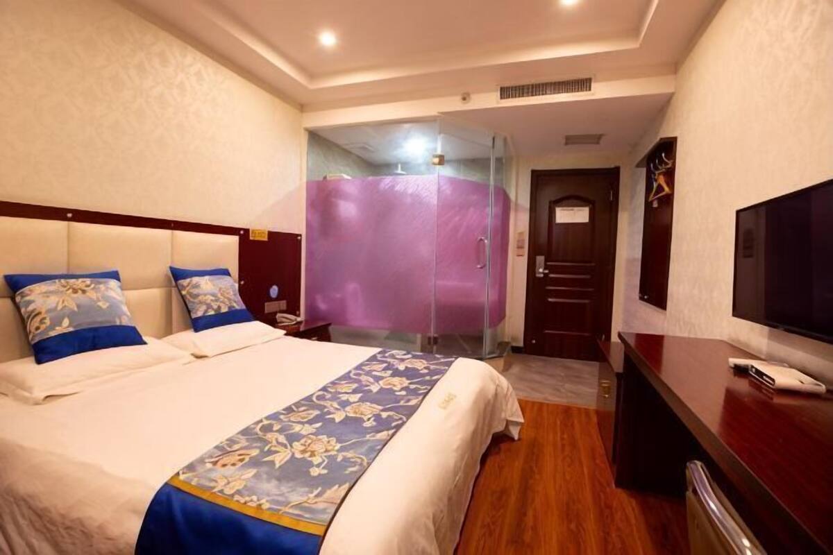 Une chambre d’hôtel équipée d’un lit, d’une télévision, d’un bureau et d’un espace douche.