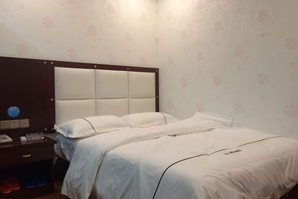 Ein Hotelzimmer mit einem großen Bett, einem Nachttisch mit Telefon und einer Wanduhr.