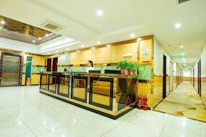 A spacious hotel lobby with a reception desk, a large mirror, and a fire extinguisher. - Zhengzhou Yaxin Hotel (Leshang Plaza) (Zhengzhou)
