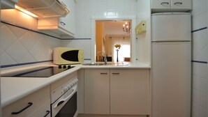 A compact kitchen with white cabinets, a microwave, an oven, and a refrigerator. - PLAYA GRANDE 34 - Two Bedroom Apartment, Sleeps 5 (Punta del moral)
