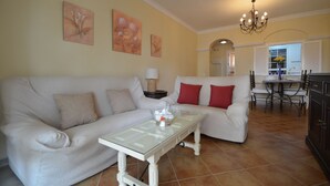 A living room with a white sofa, a glass coffee table, and a chandelier. - PLAYA GRANDE 34 - Two Bedroom Apartment, Sleeps 5 (Punta del moral)