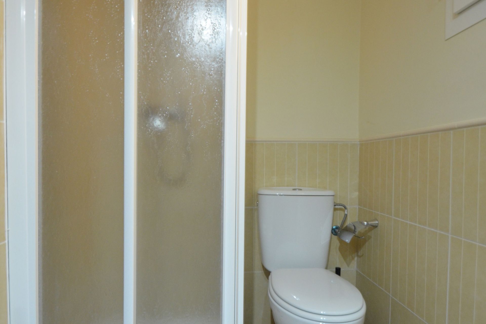 A bathroom with a toilet and a shower area.