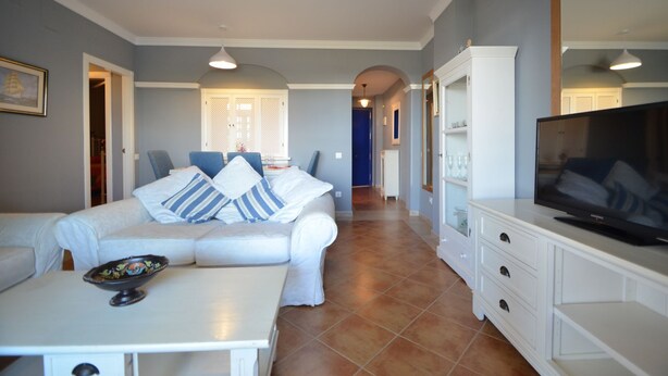 A living room with a sofa, coffee table, TV, and a dining area with chairs and a table. - LA MARINA 3 21 - Two Bedroom Apartment, Sleeps 5 (Punta del moral)